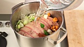 Roast ham, vegetables and spices being covered with cold water