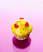 Muffin with yellow icing and sugared jelly hearts