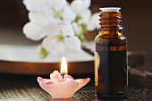 Bottle of scented oil, beside a candle, close-up