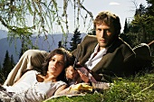Junges Paar isst Brotzeit auf Bergwiese