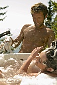 Young couple, woman in tub splashing water