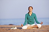 Junge Frau macht Yoga am Strand