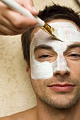 Mann bei Kosmetikbehandlung (Gesichtsmaske wird aufgetragen)