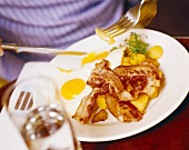 Person eating fried potatoes, eggs and bacon