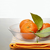 Tangerines with leaves in glass bowl