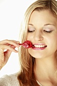 Young woman holding wrapped candy between teeth, close-up