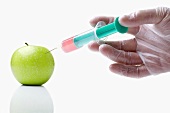 Person injecting liquid in apple