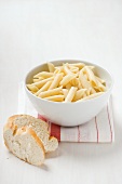 Penne in a bowl, white bread