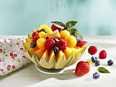 Sprinkling fruit-filled melon with icing sugar