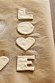 Cut-out 'LOVE' biscuits on baking parchment