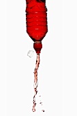 Roter Energy Drink spritzt aus Flasche