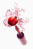 Pomegranate juice splashing out of bottle