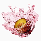 Half a plum with splashing plum juice