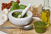 Pesto in mortar surrounded by ingredients