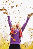 Woman throwing autumn leaves in the air