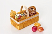 Pastries & sugar eggs in Easter basket, coloured eggs beside it