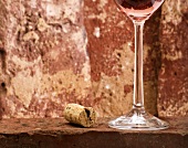 Wine cork and glass of rosé wine on brick