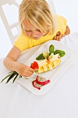 Girl sitting at table in front of plate of fruit