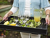 Woman carrying tray of lemonade and glasses
