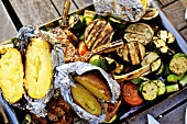 Barbecued vegetables, baked potatoes, lamb chops on barbecue tray