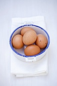 Several brown eggs in pan on tea towel