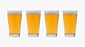 Four glasses of lager side by side