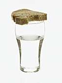 Glas Wasser und angebissene Brotscheibe