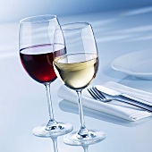 Glass of white wine and glass of red wine beside place-setting