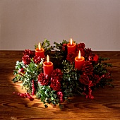 Christmas wreath decorated with red-coloured pine cones and lit candles
