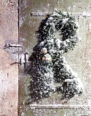 Kranz und Zweige mit Kunstschnee an  alter Tür