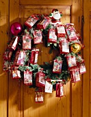 Christmas wreath decorated with gift bags hanging on door