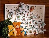 Advent calendar made from gift bags hanging on wall with teddy bear
