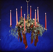 Adventsgesteck, hängend vor blauem Hintergrund, rosa Kerzen