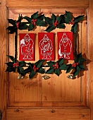 Drei mit Weihnachtsmännern bestickte rote Stoffrechtecke an der Tür