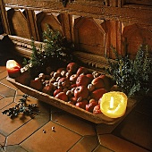 Terrakotta  Schale am Boden, Äpfel und Nüsse, zwei Kerzen, Tannenzweige