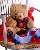 Teddybär mit karierter Schleife auf Stuhl