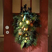 Weihnachtliches Gesteck an der Tür mit Äpfeln und Tannenzapfen