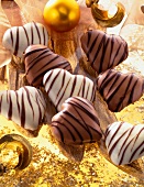 Close-up of white and brown heart shaped honey chocolates on golden foil