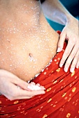 Close-up of woman taking care of her belly by rubbing sea salt on it 