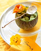 Melon fruit bowl with melon balls decorated with nasturtium flower on glass plate