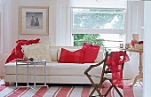 Holzstuhl, dahinter ein weisses Sofa mit roten Kissen, grosses Fenster