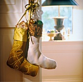 White and golden coloured stocking hanging on wall with decorations
