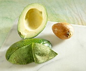 Halved avocado partially peeled with a stone on table