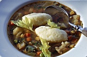 Gemüsesuppe mit Griesklösschen. Close up. Löffel auf dem Teller.