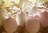 Pastellfarbene Eier mit verknoteten Bastfäden (im Eiertablett)
