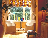 Sitting area in bay window with white chairs and stained glass decoration