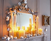 Spiegel ist mit silberfarb. Blätterranke, Steinen + vielen Kerzen dek.