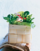 Green asparagus with strawberries in wooden basket