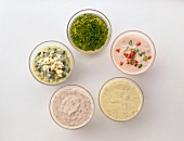 Five different dressings in glass bowls on white background
