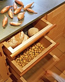 Arbeitsplatte, darunter Schubfächer aus Holz für Brot und Gemüse